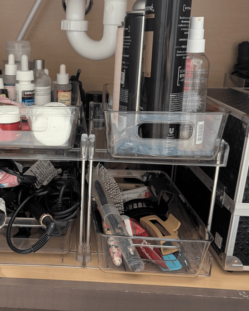 Clear two tier acrylic organizer holding bathroom essentials in a cabinet shared by three kids