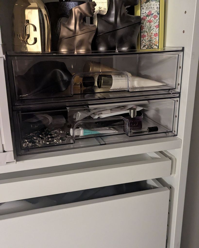 Clear acrylic drawer organizers holding jewelry and accessories on closet shelf