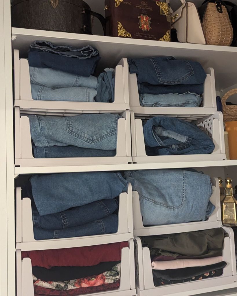 Stackable white shelf bins organizing folded jeans and clothing on closet shelf